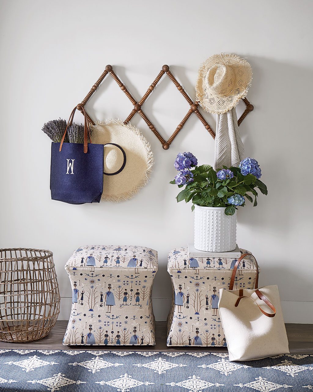 An upholstered ottoman completes this entryway, just underneath a wall mounted coat rack