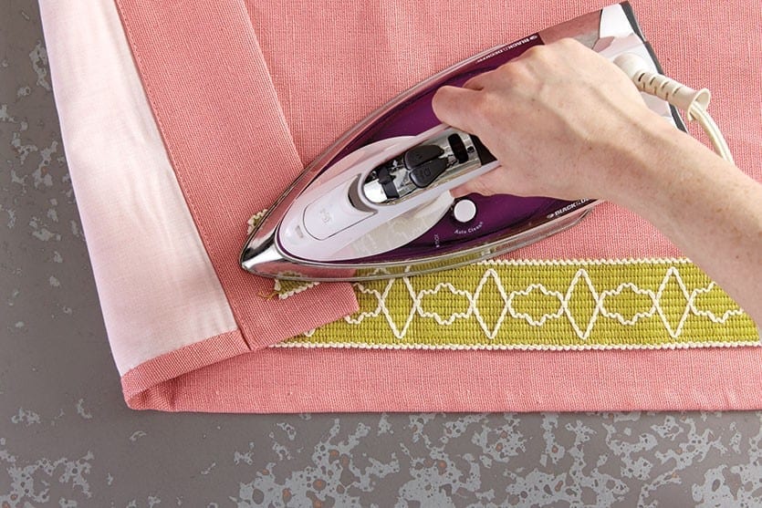 Once the trim is secured in your first section, turn the corner of the panel over to steam the edge.