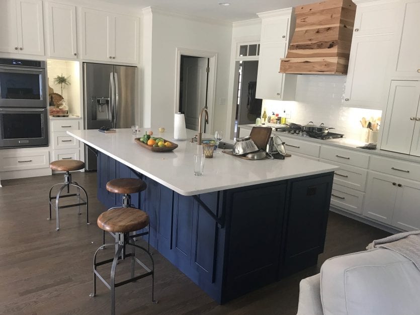 Navy kitchen island in white kitchen with white countertops