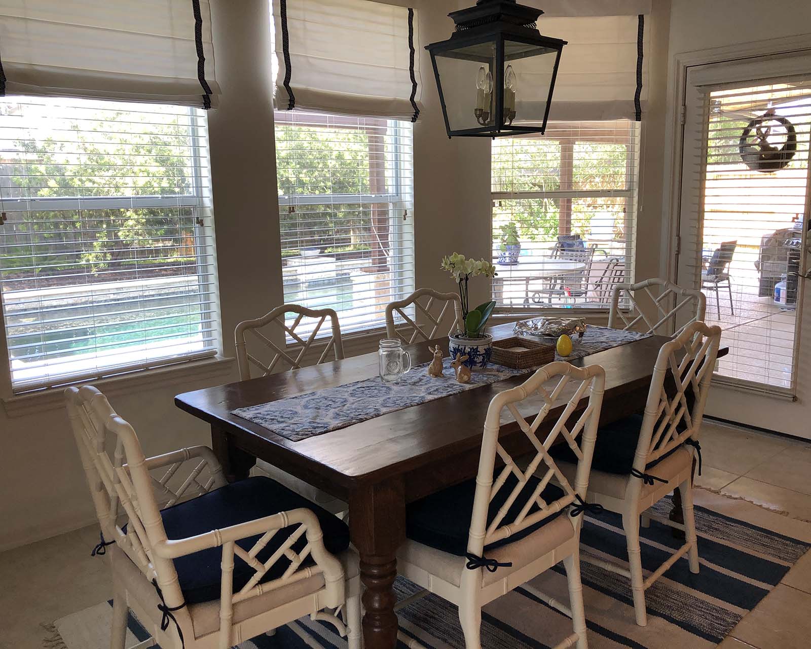 Mirna's dining room with navy blue lantern, roman shades, and striped rug